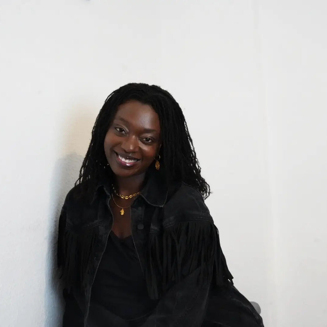 Woman wearing a black fringed jacket against a white background
