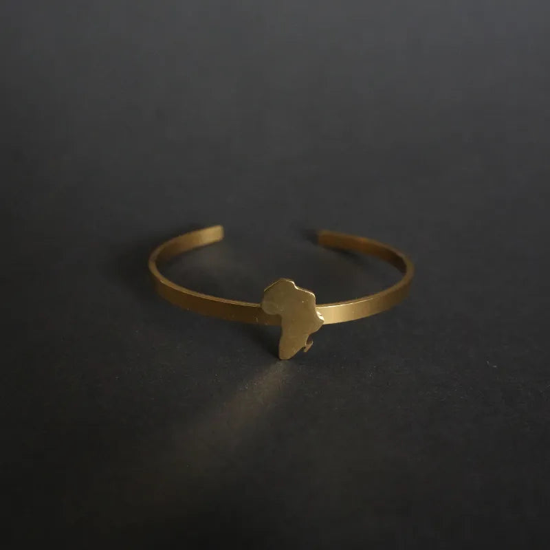 Minimalist African map bangle in polished gold-tone metal, featuring open cut-out design of the continent, symbolic statement piece inspired by heritage and identity.