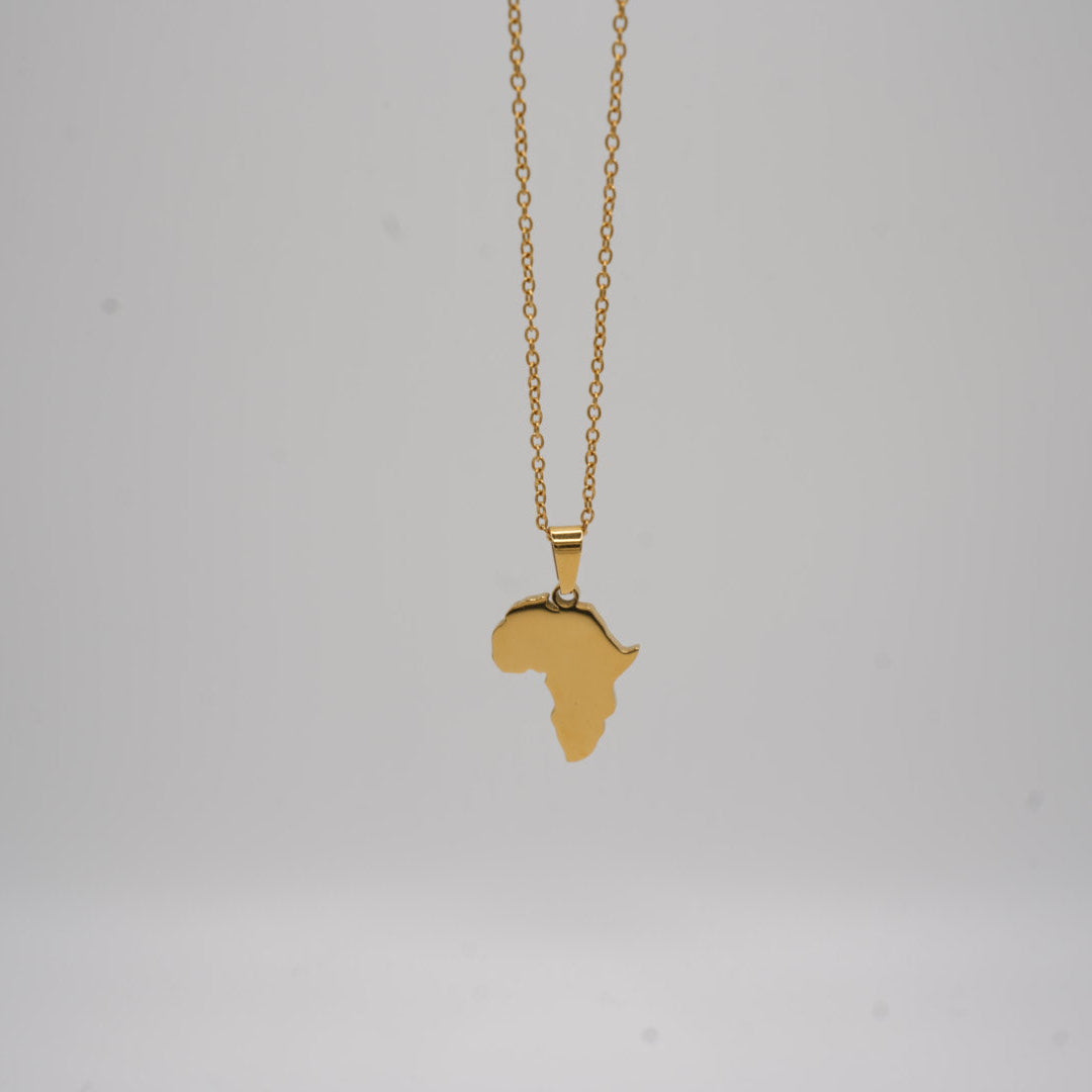 Gold necklace with a pendant shaped like the African continent on a light gray background