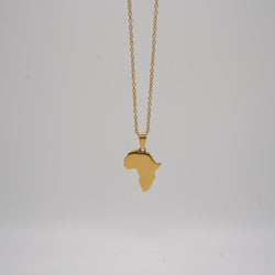 Gold necklace with a pendant shaped like the African continent on a light gray background