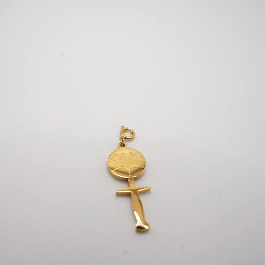 Gold fertility doll pendant on a light gray background