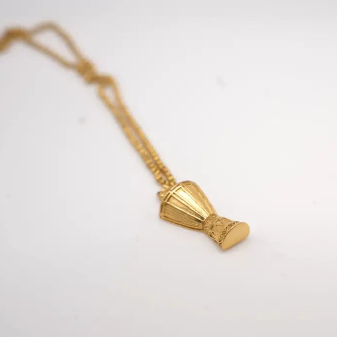 Gold necklace with a djembe-shaped pendant on a white background