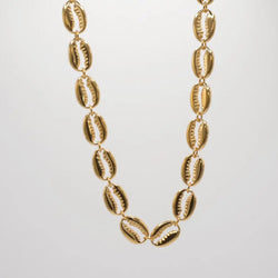 Gold necklace with shell-like cowries links on a light gray background