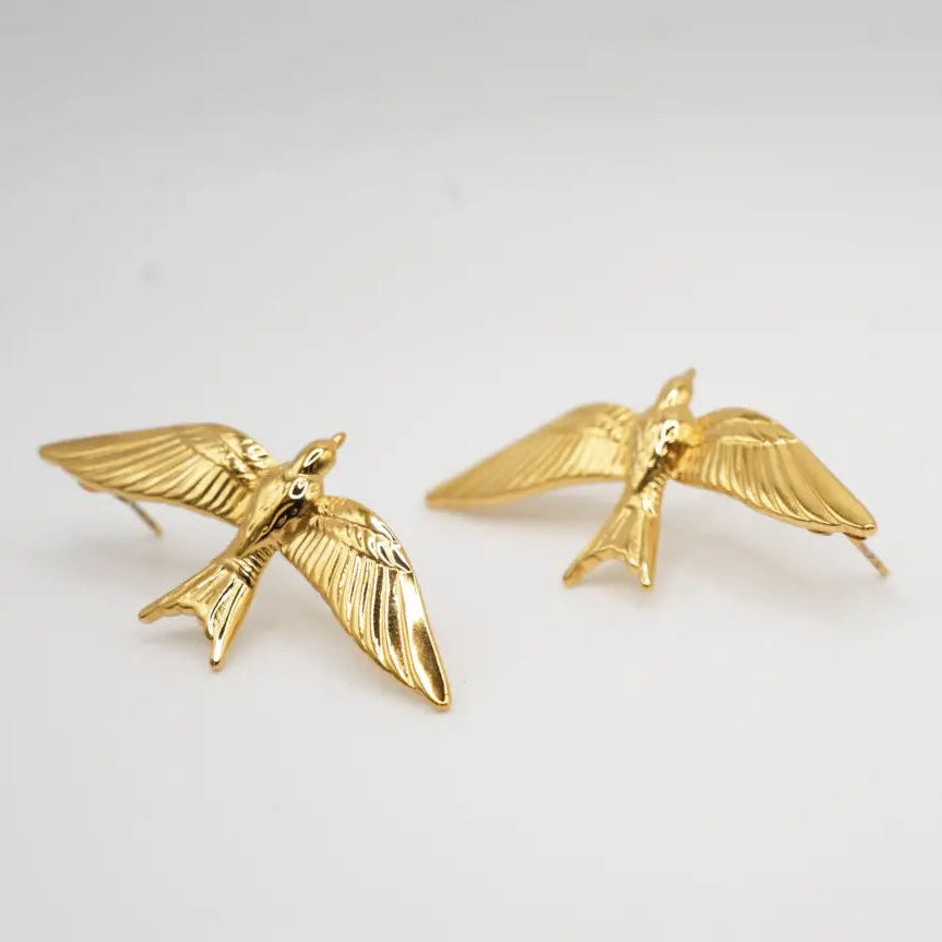 Gold bird-shaped earrings on a light gray background