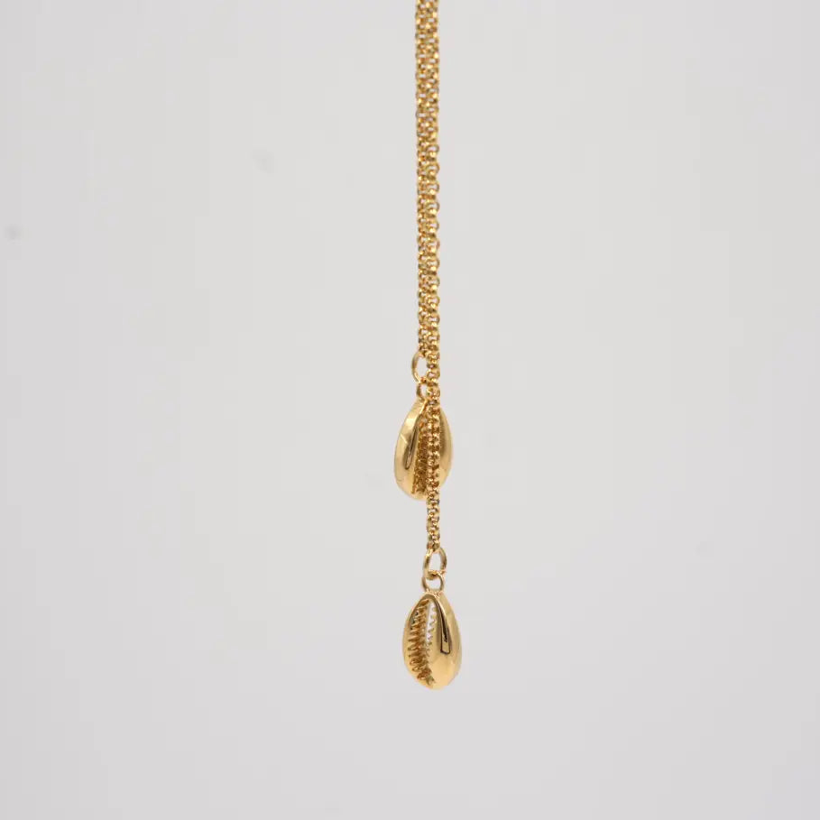 Gold necklace with cowrie shell pendants on a light gray background