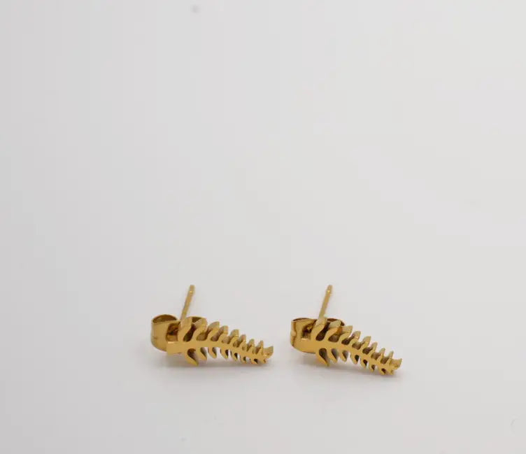 Gold skeleton bone-shaped earrings on a light gray background