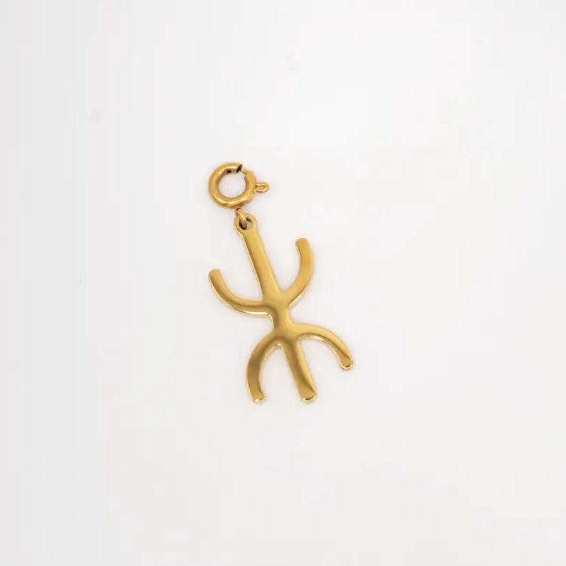 Gold yaz charm on a white background.  Yaz symbol of the “Free Man,” the name the Amazigh people use for themselves. 
