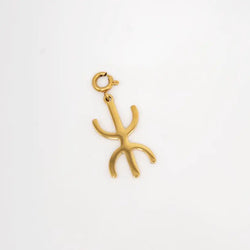 Gold yaz charm on a white background.  Yaz symbol of the “Free Man,” the name the Amazigh people use for themselves. 