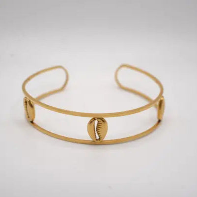 Gold bracelet with cowries shell designs on a light gray background. African bracelet design form doore dasi