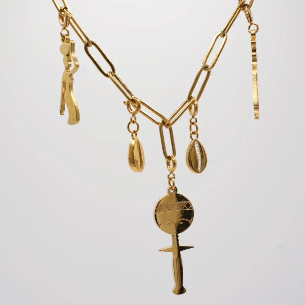 Gold necklace with various african pendants on a light gray background