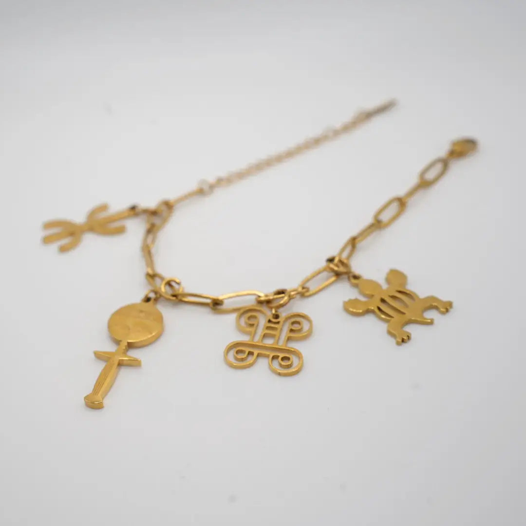 Gold bracelet with various african adinkra charms on a light gray background