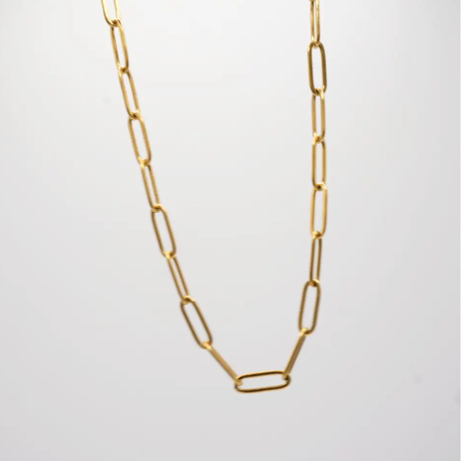 Gold chain necklace on a light gray background