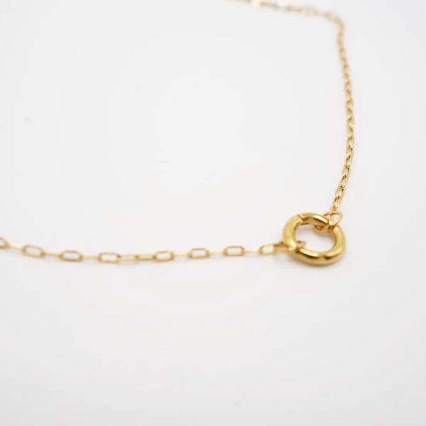 Gold necklace with a small round clasp for charms on a white background