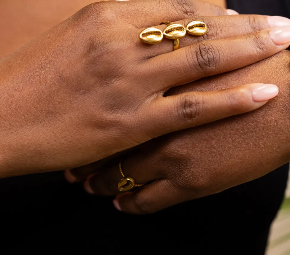 Close-up of a hand wearing gold rings on a neutral background
