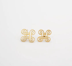 Gold earrings with a decorative design on a white background, inspired by adinkra symbol