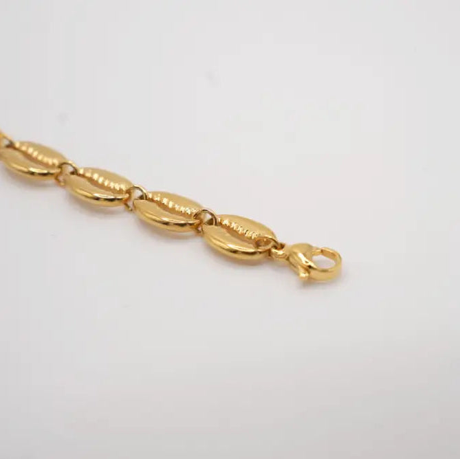 Gold cowries bracelet on a light gray background