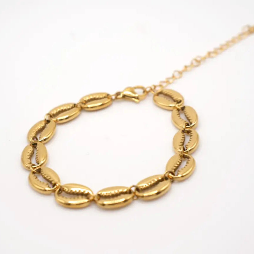 Gold chain bracelet with cowries on a white background