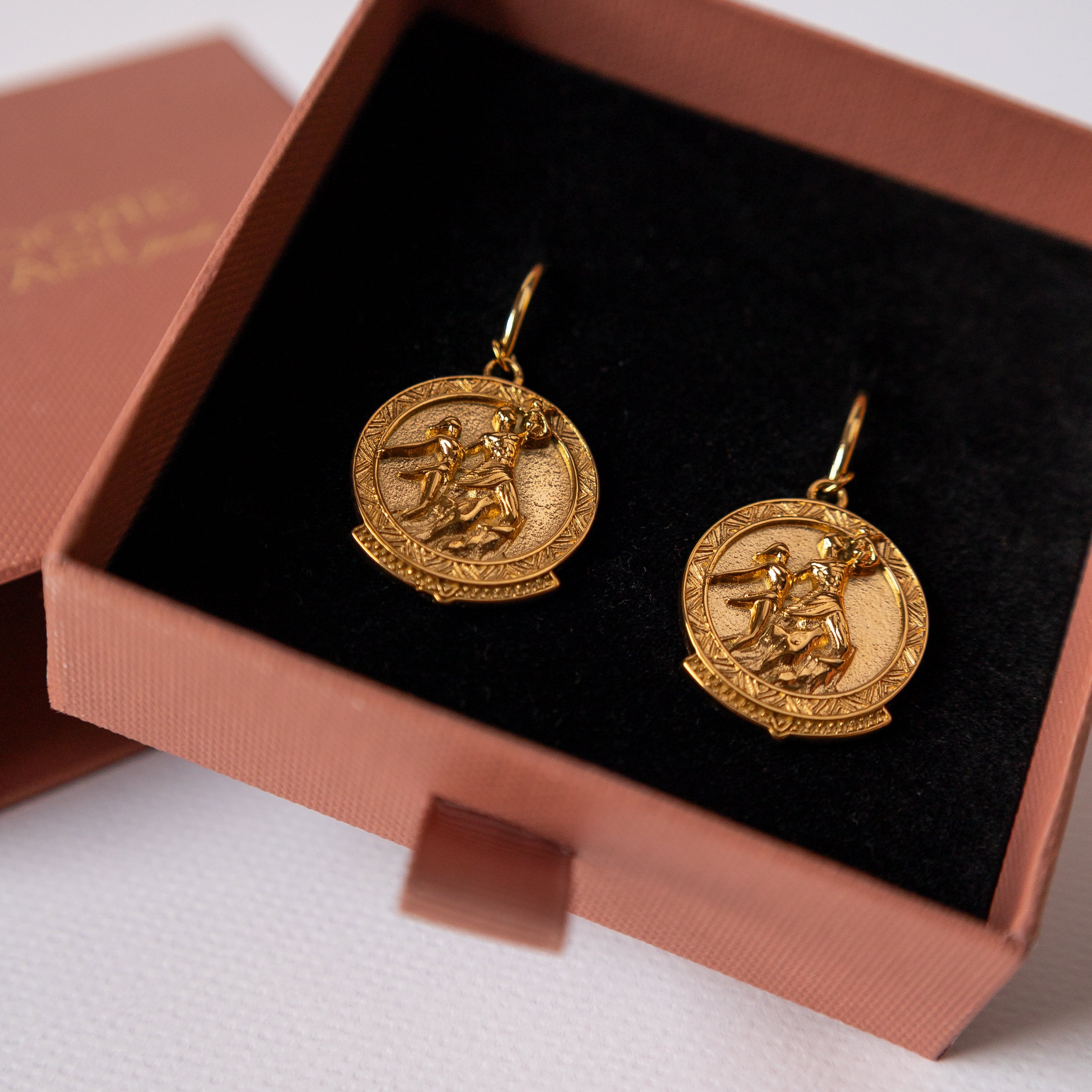Gold earrings in a jewelry box on a light background